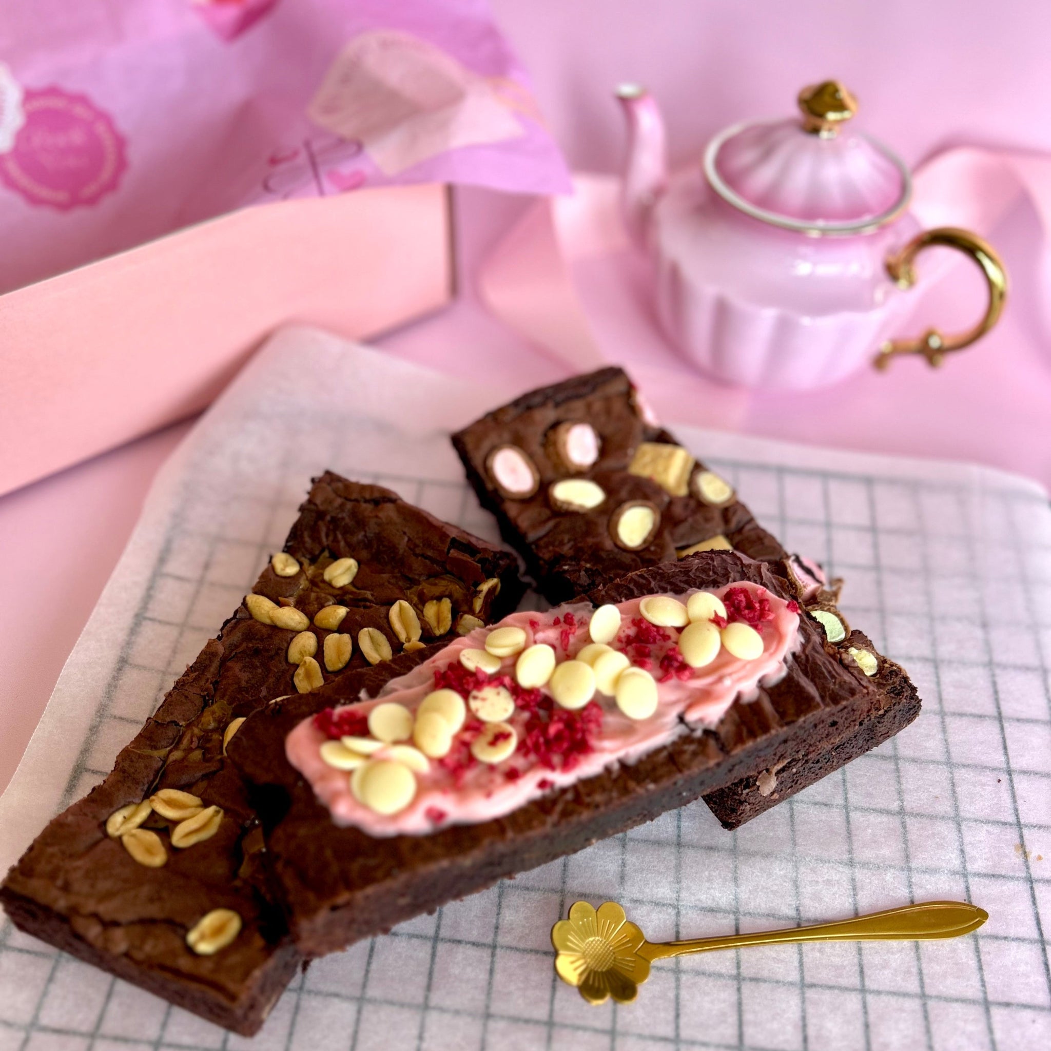 three brownies stacked in front of high tea pink teapot and gift box