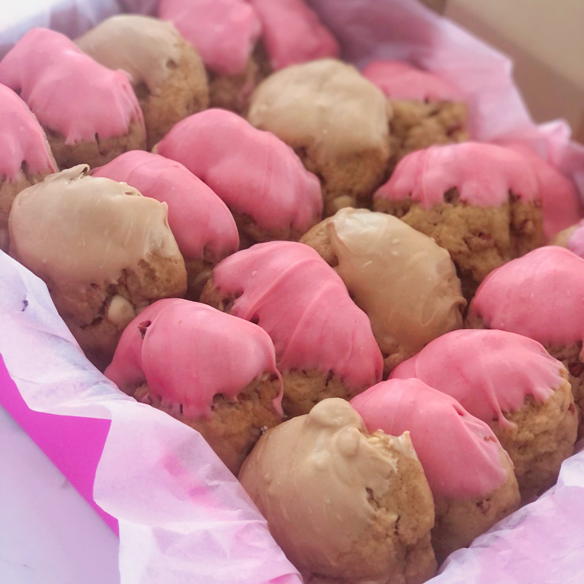 Pink and gold mini baby shower cookies displayed in a pretty pink gift box