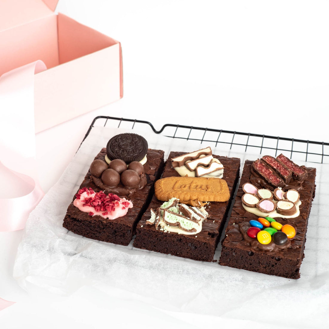 Brownie slab showing a variety of flavours on top on baking paper with pretty gift box in background