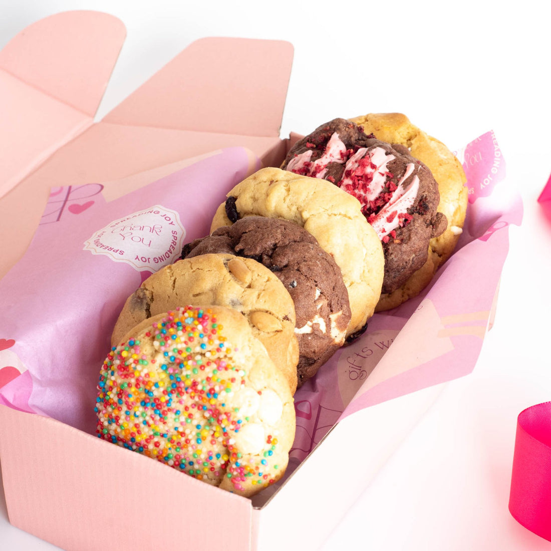 Front view of fresh baked yummy cookies lined up in a birthday gift box with the lid open 