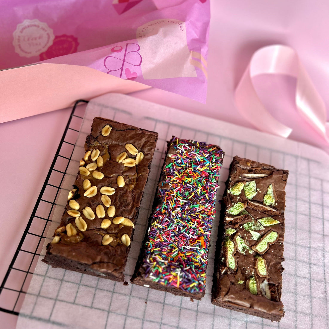 three individual brownies lined up side by side on baking paper next to a gift box hamper