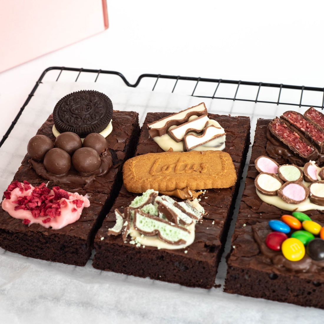 close-up view of brownie slab split in 3 with a variety of yummy assorted toppings, with a gift box ready for delivery