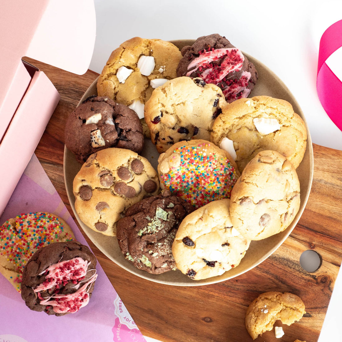 A plate of colorful chunky cookies with a gift box in the background ready for delivery