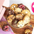 A plate of colorful chunky cookies with a gift box in the background ready for delivery