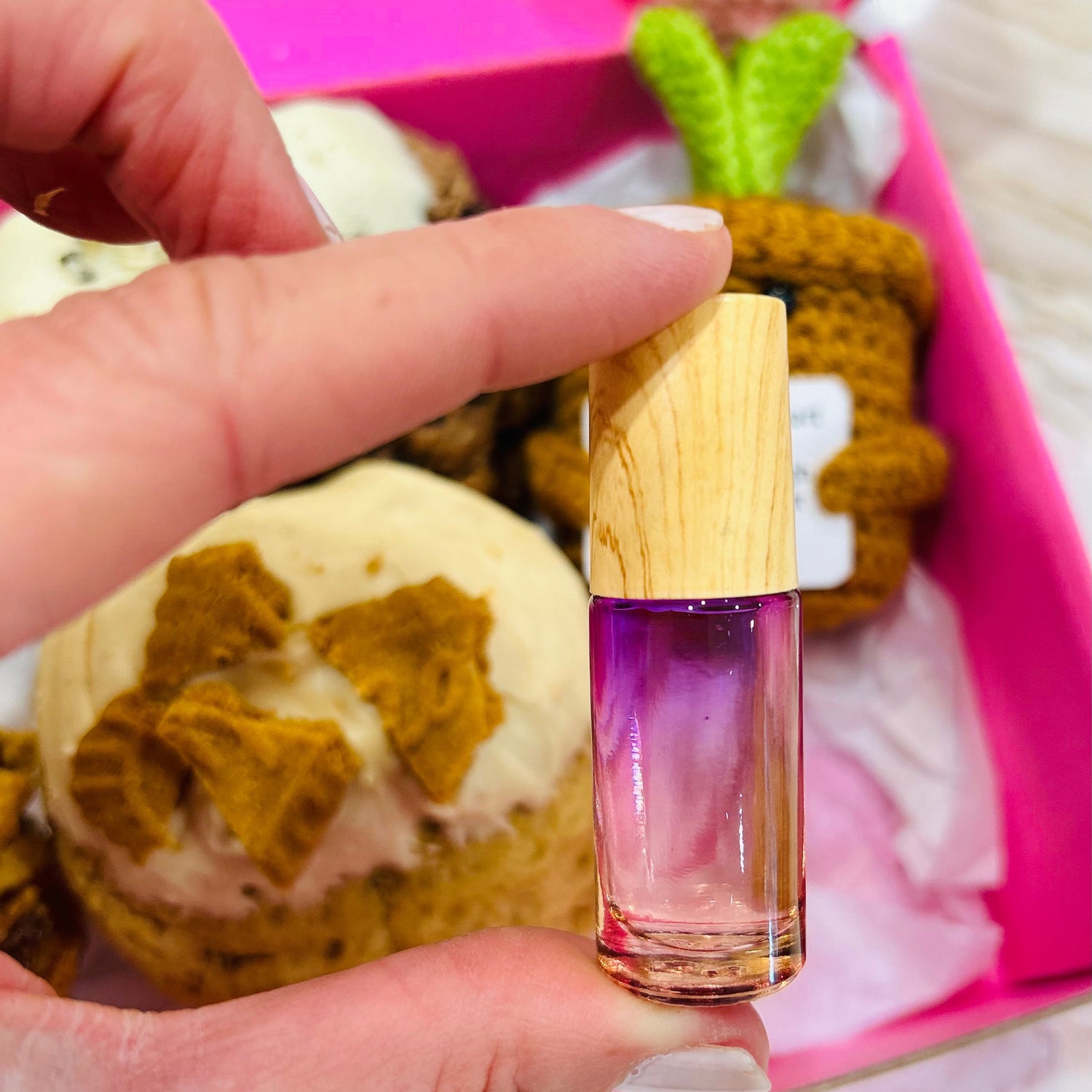 Hand holding essential oil roller in fron tof cookie gift box