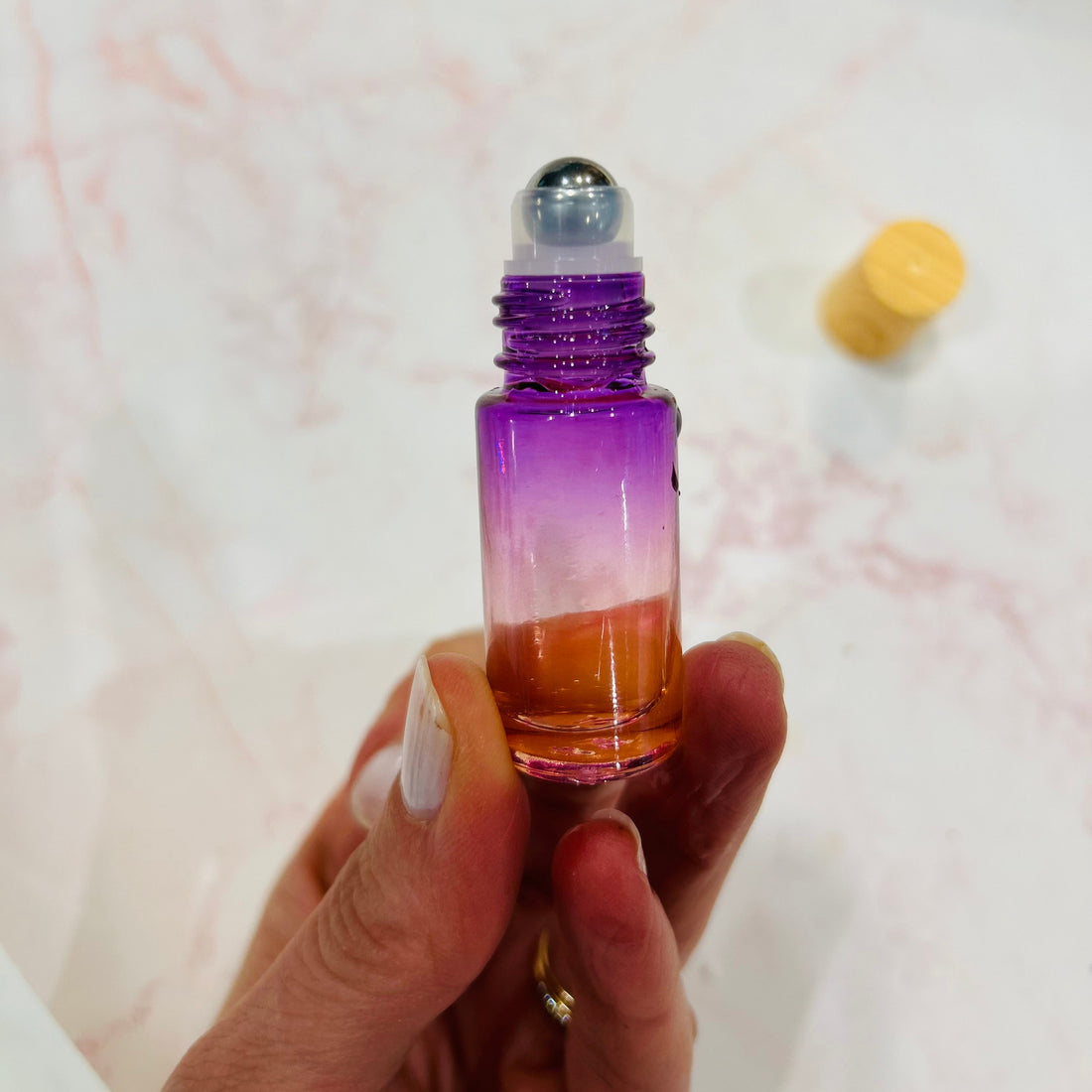 Hand holding up an essential oil roll-on with the lid removed
