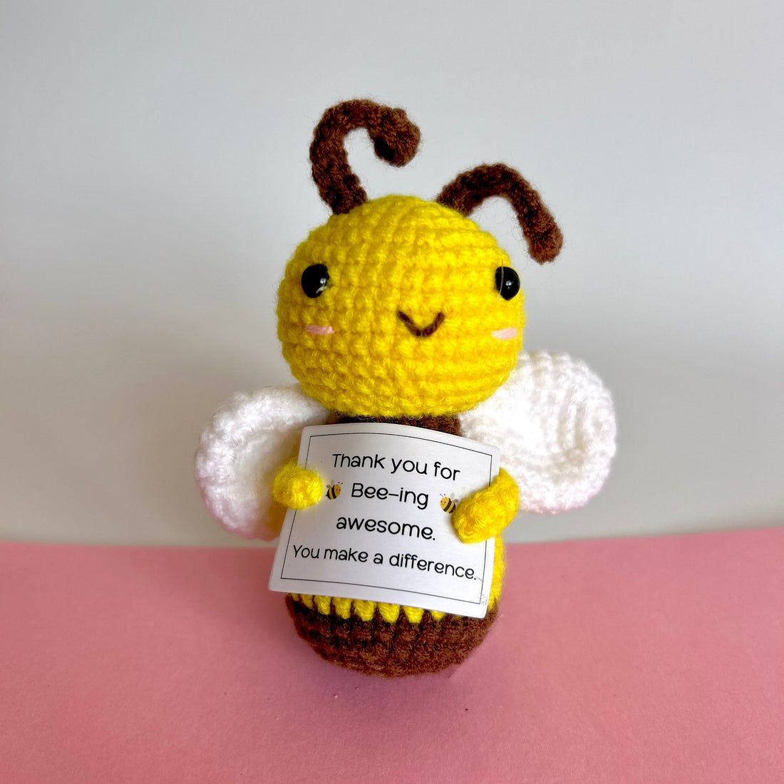 front on view of a hand knitted cute bee holding the message, Thank you for bee-ing awesome. You make a difference