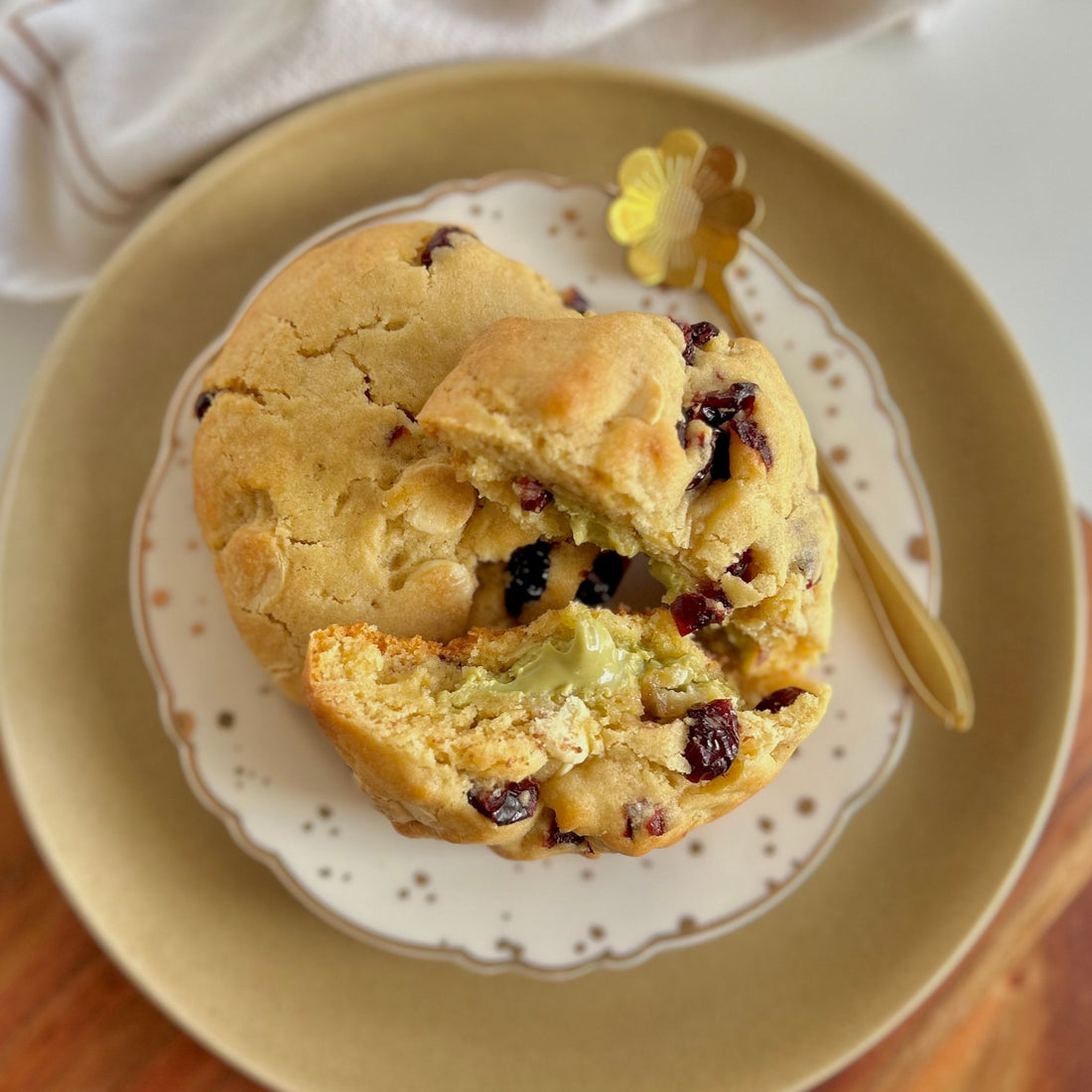 two pistachio papi cookies, one cut open to show the oozing spread on a white and gold plate